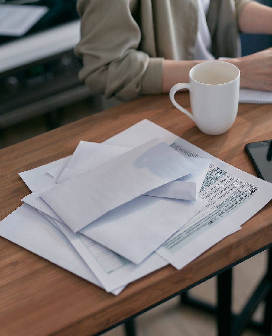 Envelopes and financial documents on a desk beside a coffee cup