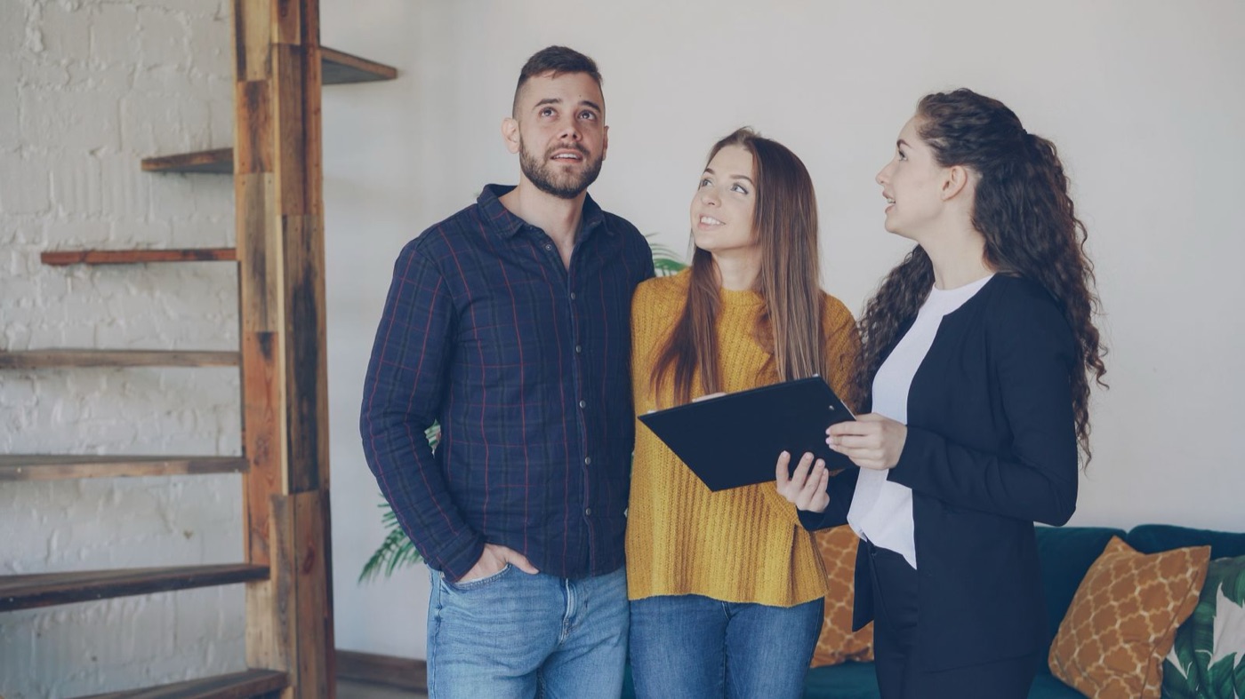 Agent talking a couple through a property, notebook out