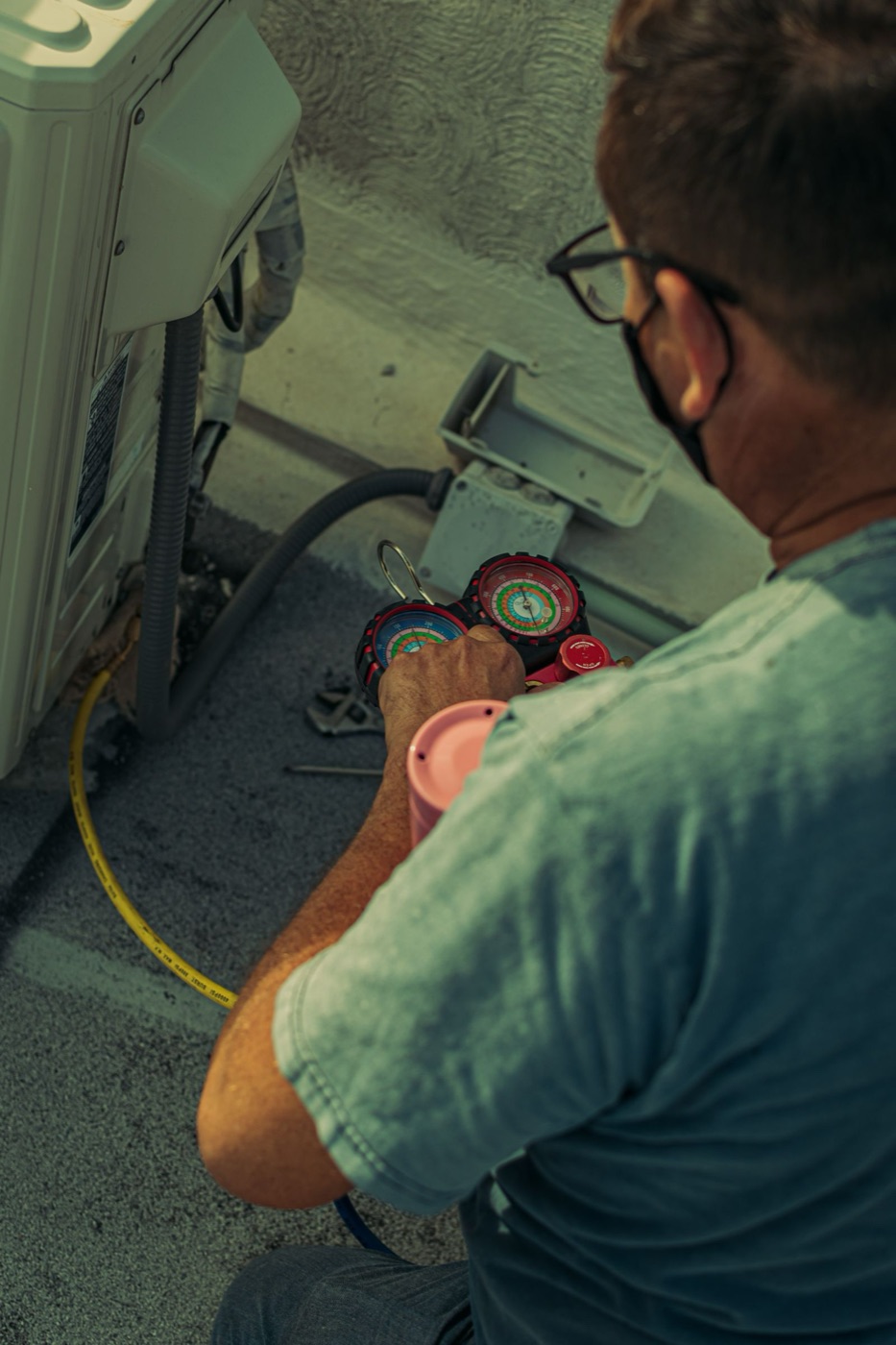 Technician's hands on service gauges during an HVAC repair