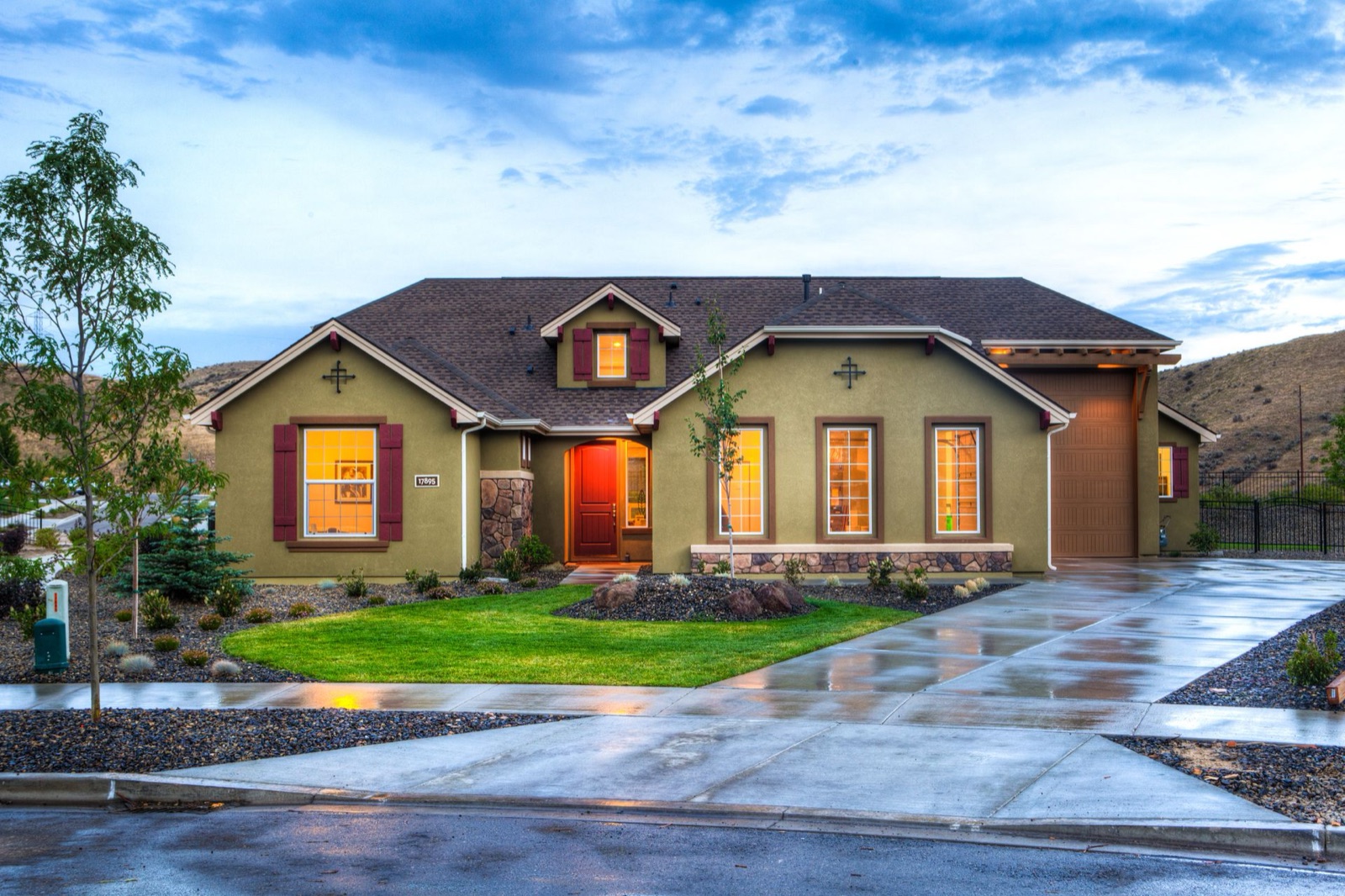 Two-story home with front porch and landscaped yard at dusk