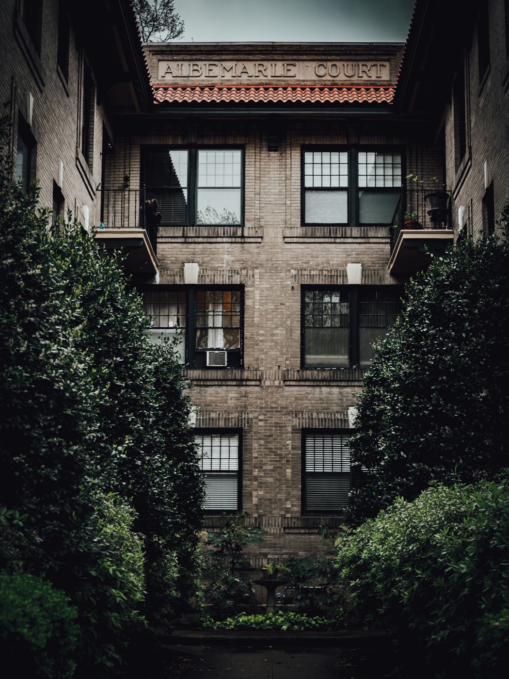 Brick apartment building with mature plantings and window units